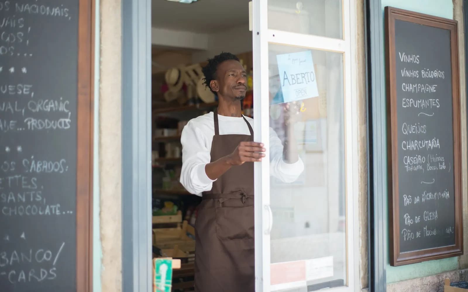 A shop owner opening up for the day, a chalkboard menu beside the door